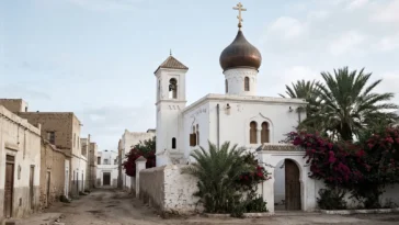 Белый православный храм с луковичной главой и звонницей среди пальм и бугенвиллей в марокканском городе