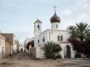Белый православный храм с луковичной главой и звонницей среди пальм и бугенвиллей в марокканском городе